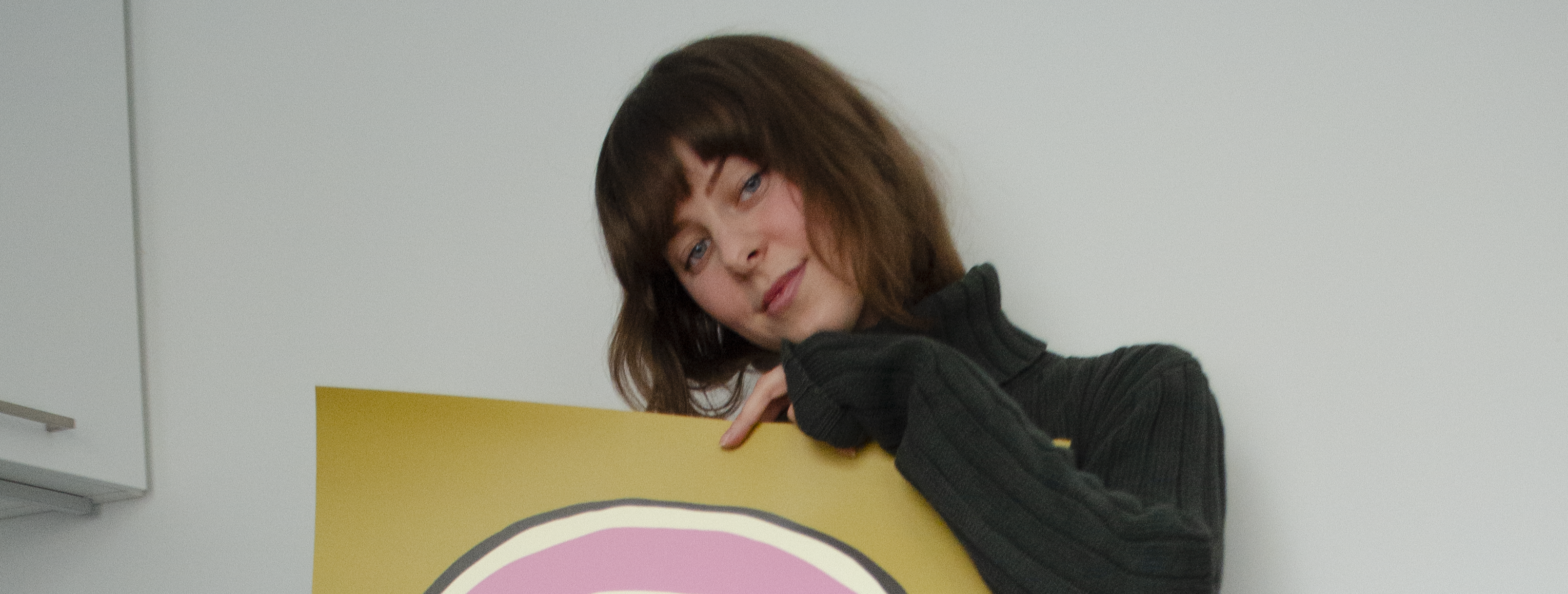 A woman holding a colorful art print in her hands.